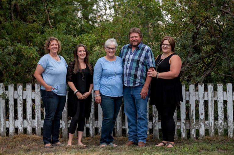 Parents and kids in front of white picket fence by Collin Stumpf Photography