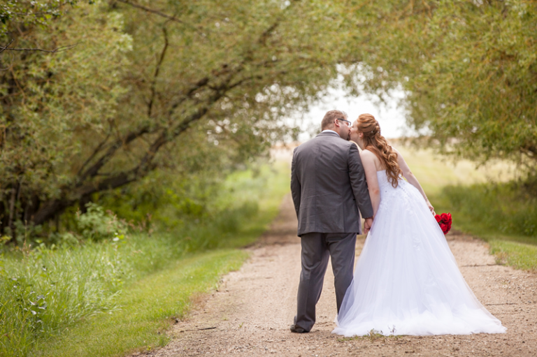 bride and groom kissing on road 