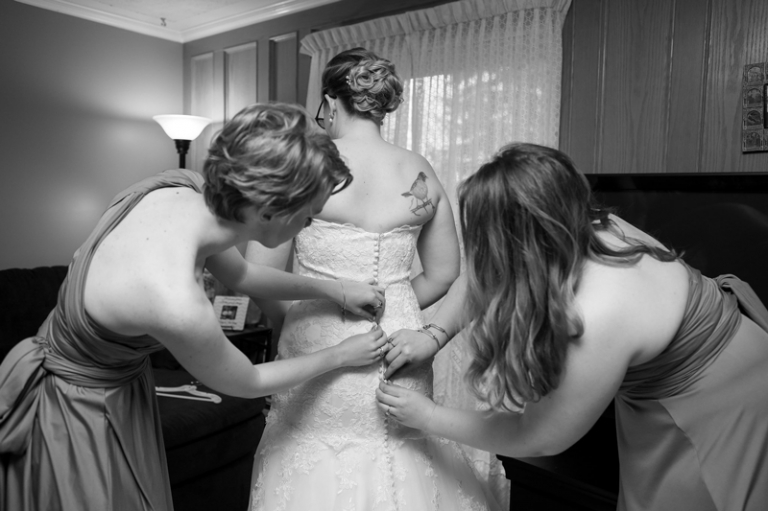Bridesmaids doing up dress in black and white